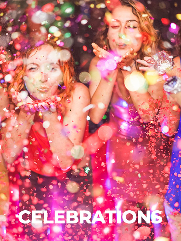 a couple of women blowing confetti