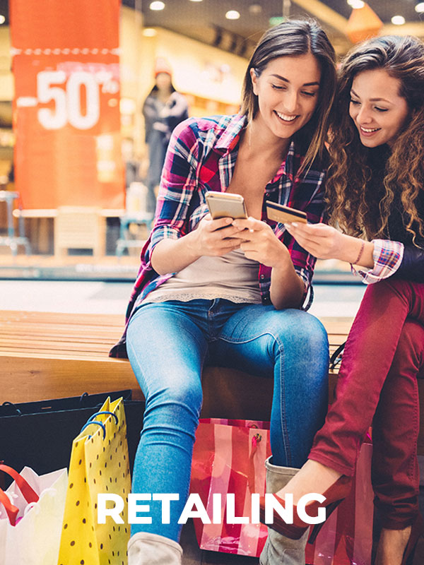 two women sitting on a bench looking at a phone