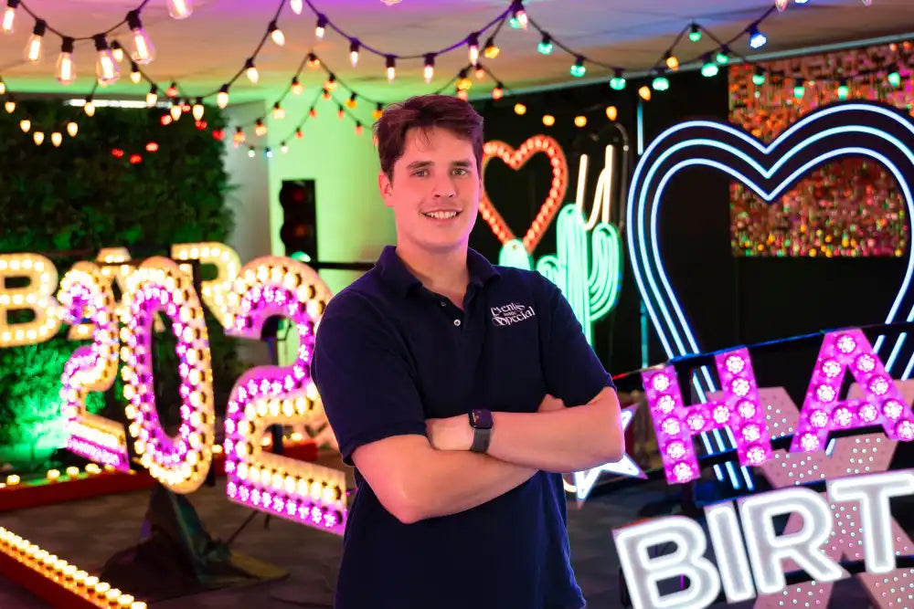 Man posing in front of neon signs.