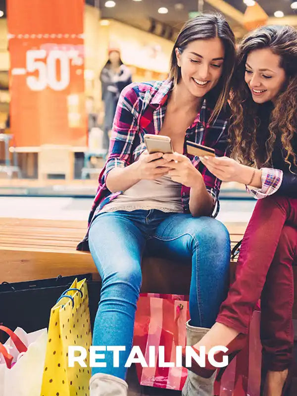 two women sitting on a bench looking at a phone
